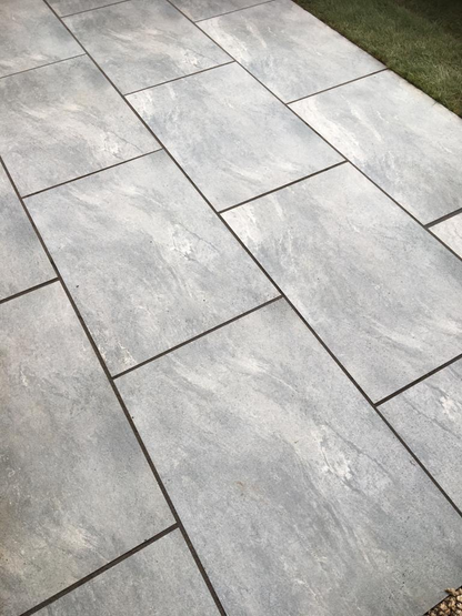 Earthcore Grey porcelain paving slabs on patio with grass