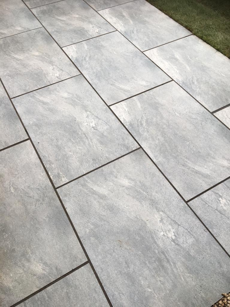 Earthcore Grey porcelain paving slabs on patio with grass